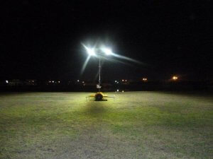 Portable solar led light tower in a green grass field at night