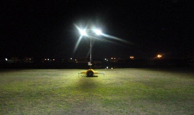 Portable solar led light tower in a green grass field at night